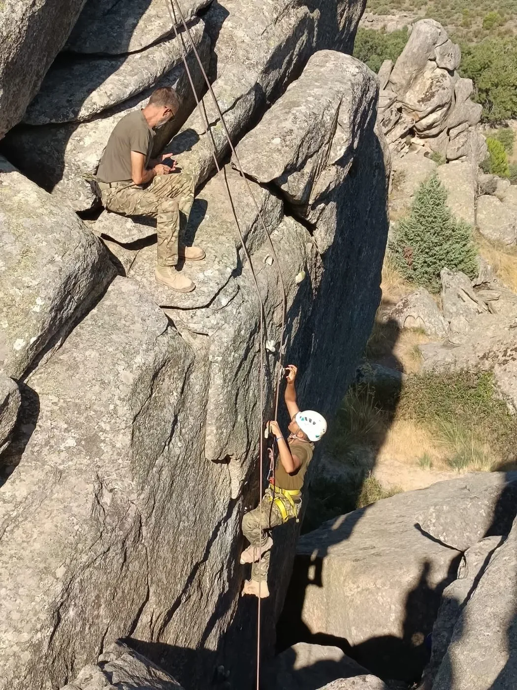 Acampado descendiendo en rappel por una pared de granito