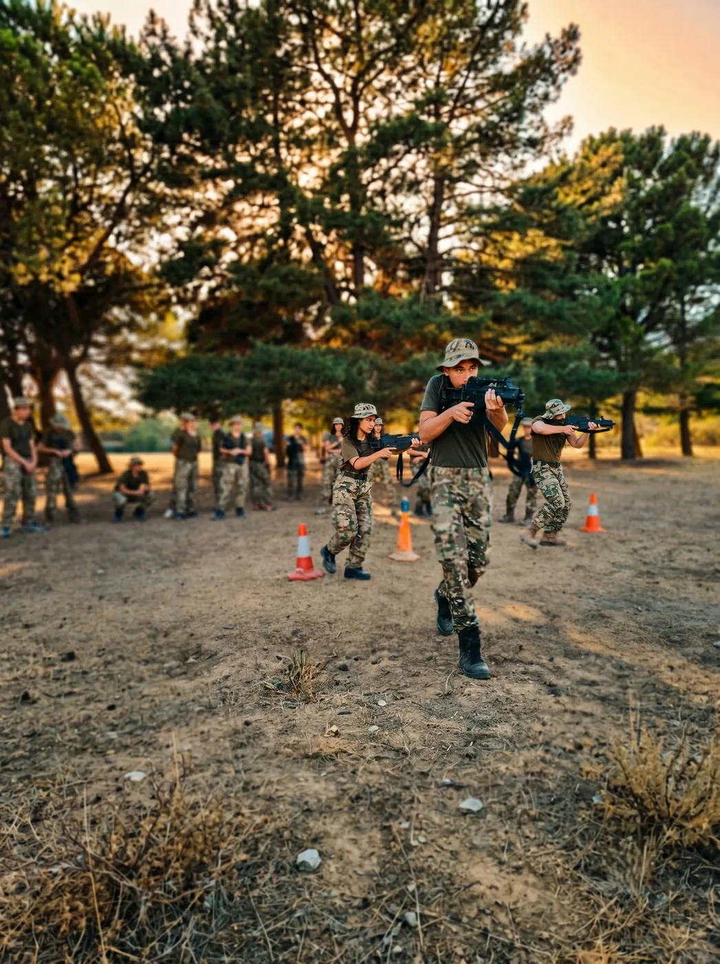 Acampados con réplicas avanzando en una simulación de airsoft al atardecer