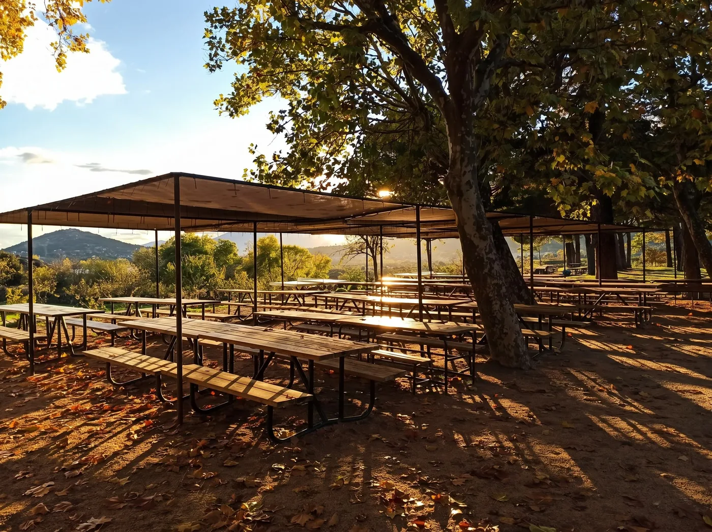 Comedor exterior del campamento con mesas bajo el toldo al atardecer