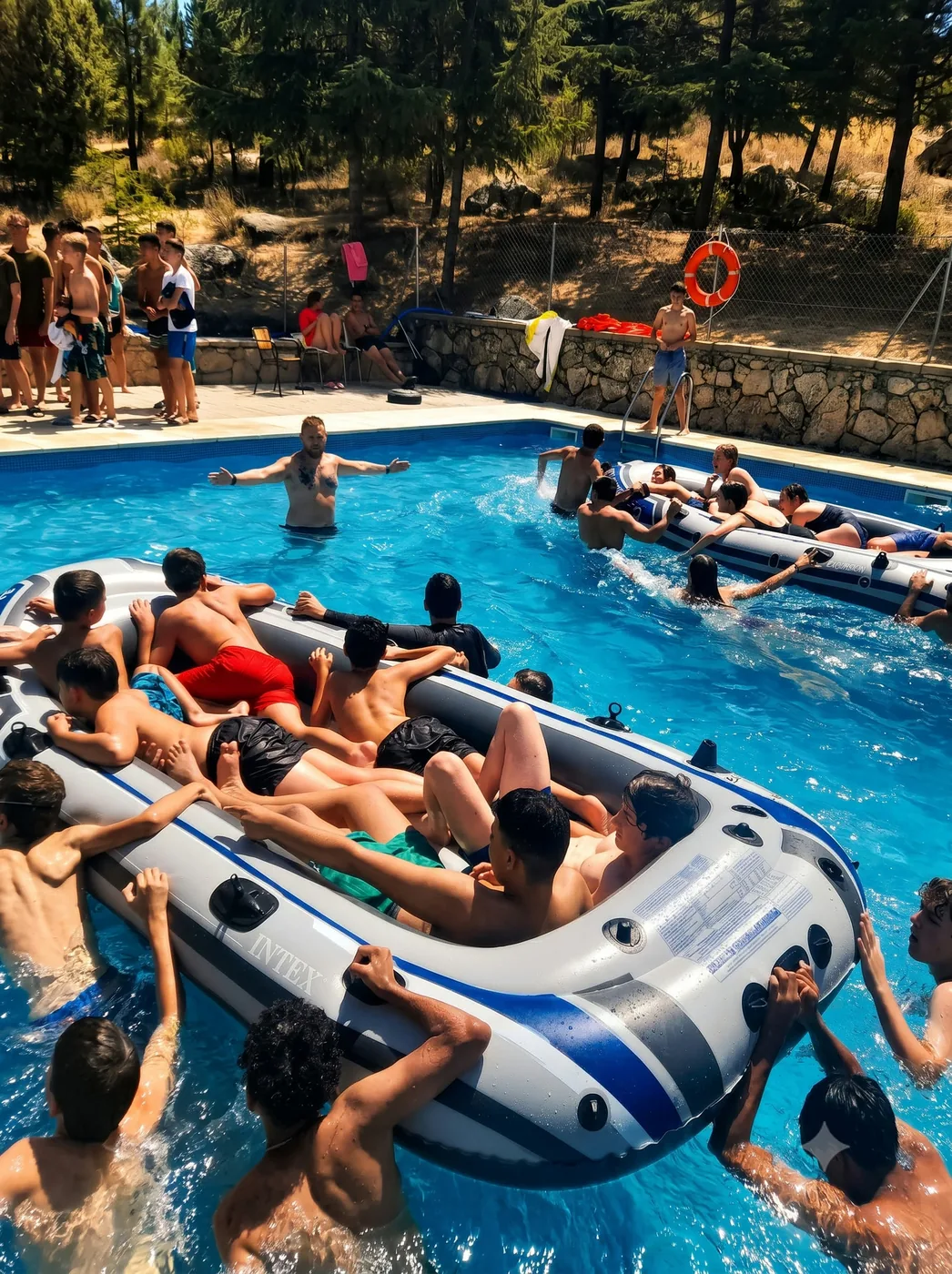 Acampados jugando con un bote hinchable en la piscina